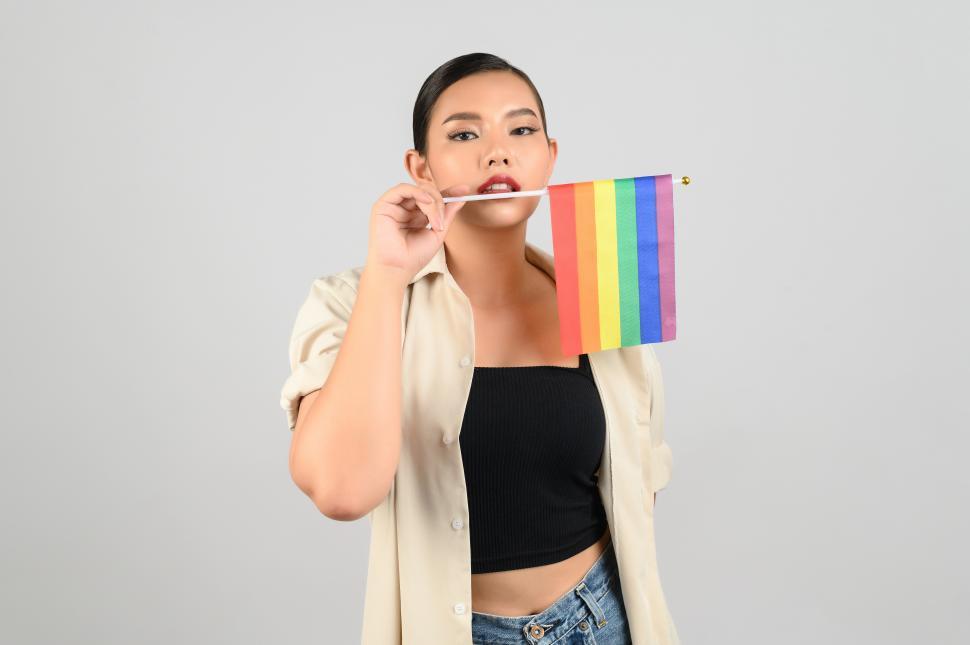 Free Image of Pretty woman celebrates LGBTQ pride with rainbow flag in hand 