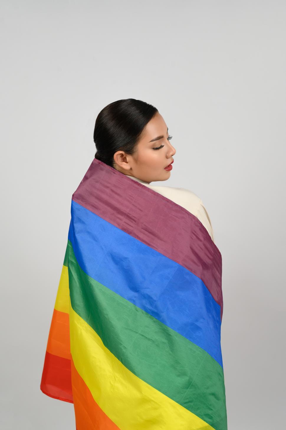 Free Image of Pretty woman poses with colorful gay pride flag on white backdrop 