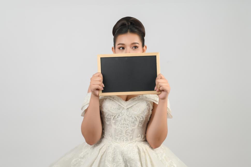 Free Image of Young asian beautiful bride pose with blank blackboard in hand 