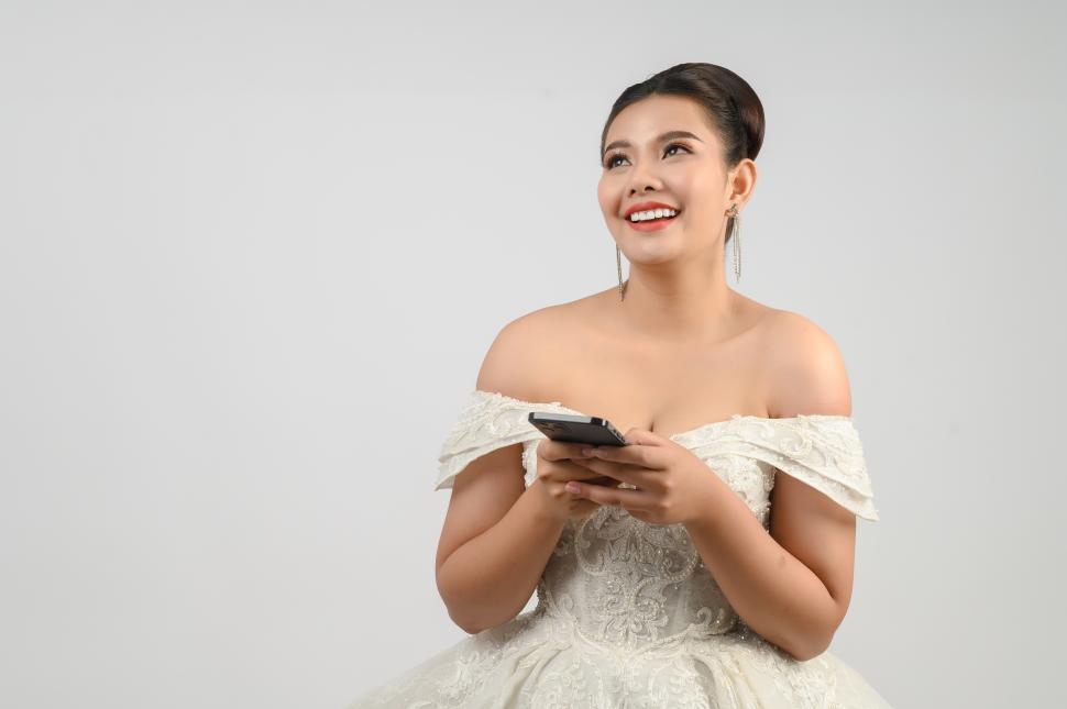 Free Image of Young asian beautiful bride posting with smartphone in hand 