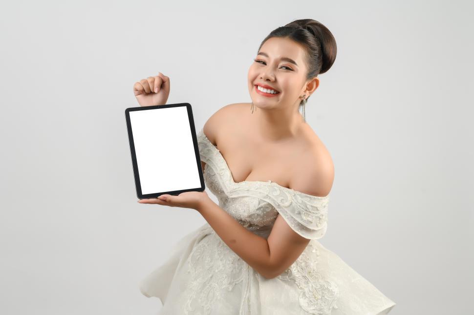 Free Image of Young asian beautiful bride pose with mockup tablet in hand 