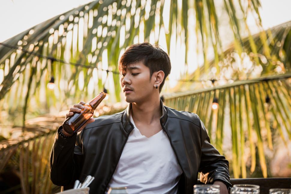 Free Image of Young man sitting at bar table toasting beer glasses dinner outdoor 