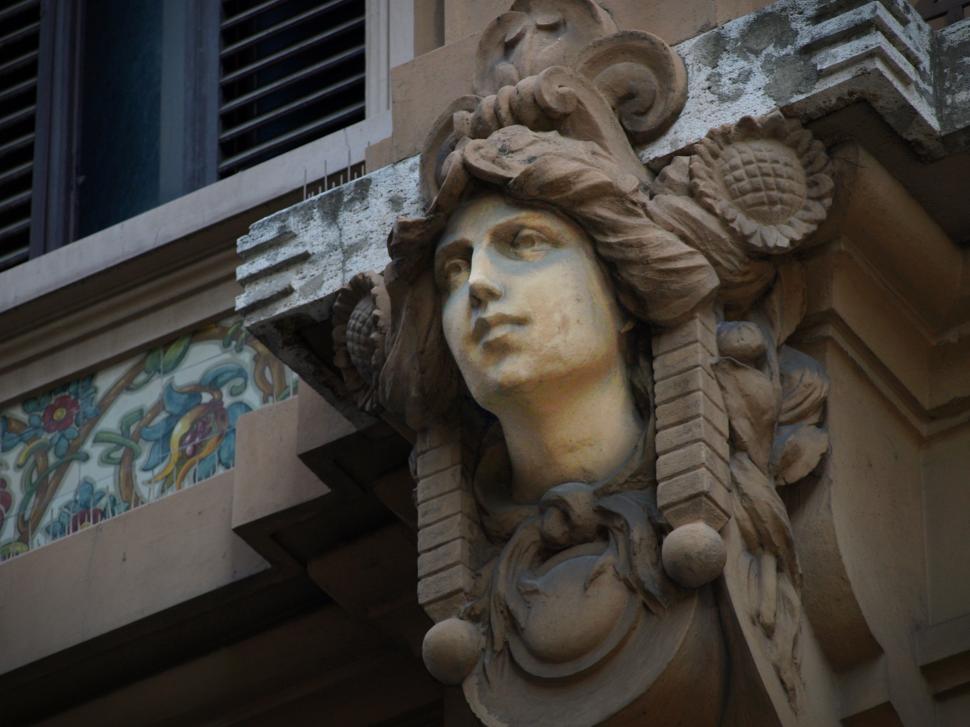 Free Image of Ornate architectural detail featuring a sculpted face on a historic building facade in a vibrant city 