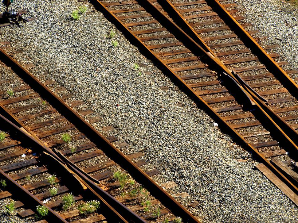 Free Image of Rusty train tracks winding through rocky terrain with small plants thriving in urban decay 