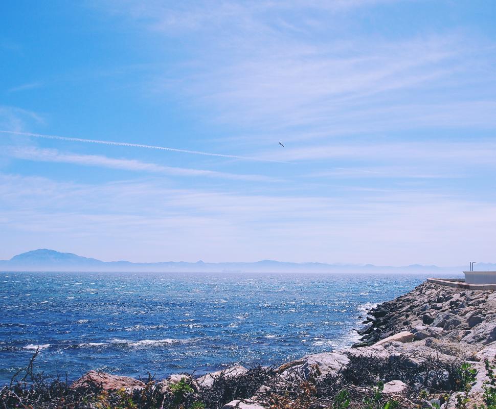 Free Image of Coastal view with blue skies and distant mountains 