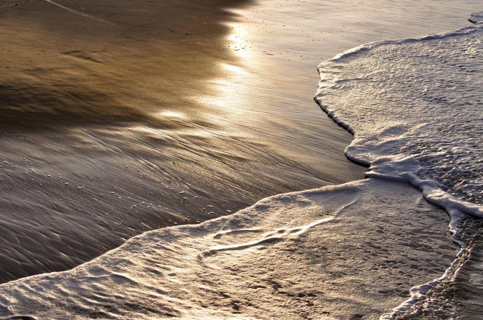Free Image of Waves gently lap at the sunset beach sand 