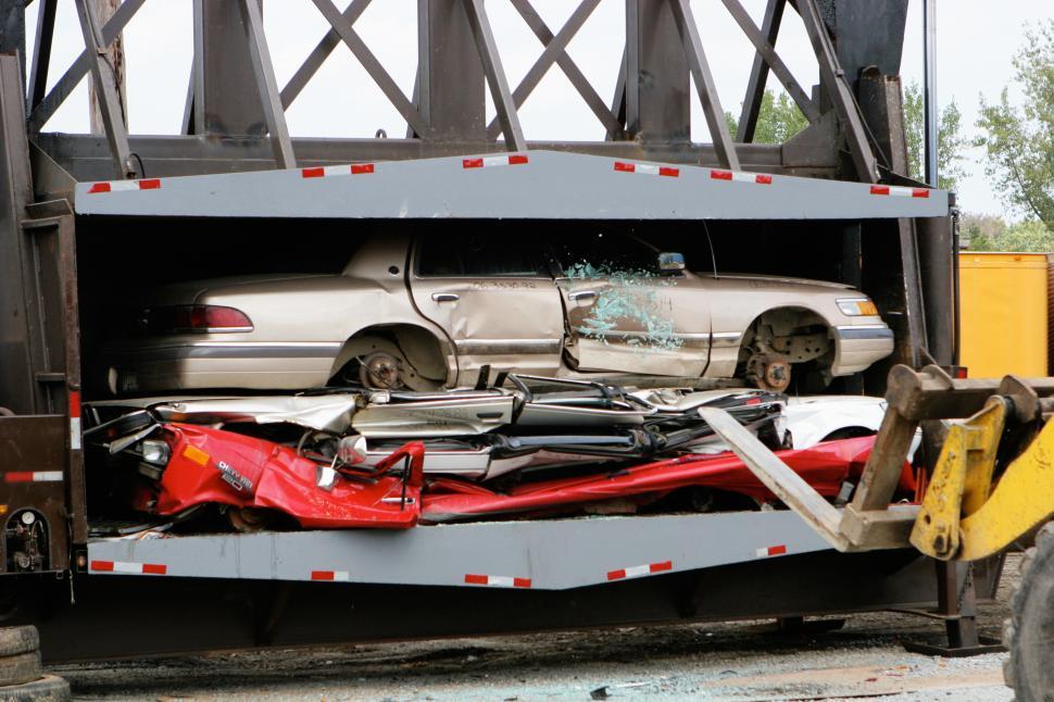 Free Image of Car recycling process taking place at a waste management facility with crushed vehicles on display 