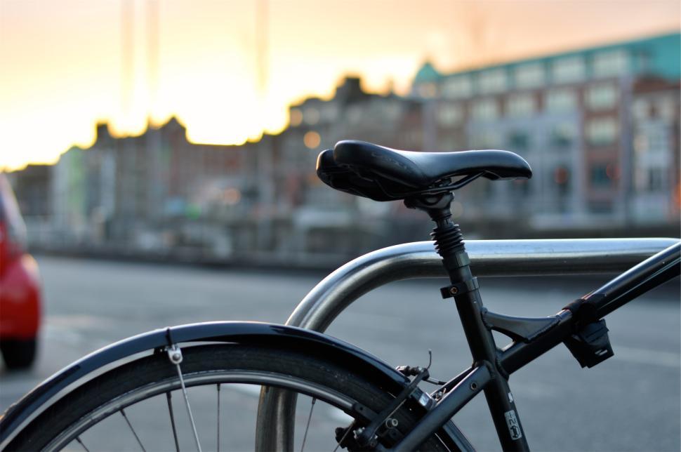 Free Image of Bicycle parked against rail with sunset in background 