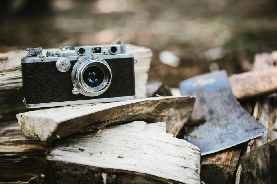 Free Image of Vintage camera resting on chopped wood beside an axe 