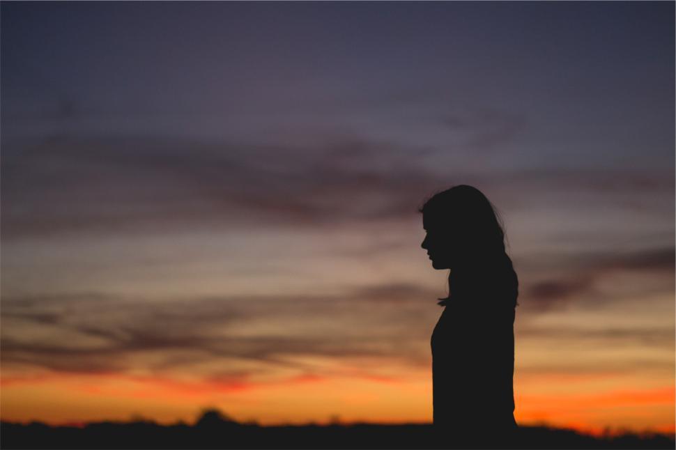 Free Image of Silhouette of a woman against a colorful sunset sky 