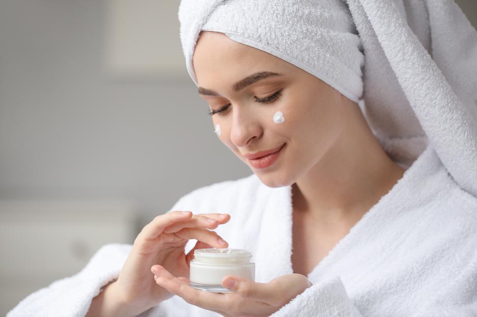 Free Image of Woman applying skincare product in cozy bathroom setting 