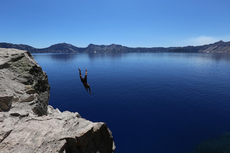 Free Image of Diver plunges into deep blue water at Crater Lake on a sunny day 