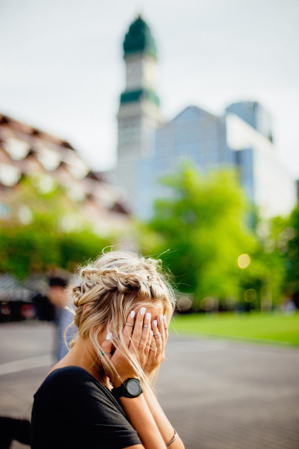Free Image of Woman with braided hair covering face in a city park during daylight 