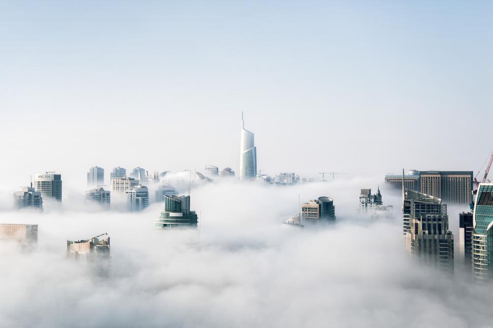 Free Image of City skyline emerging from dense fog in the morning light 