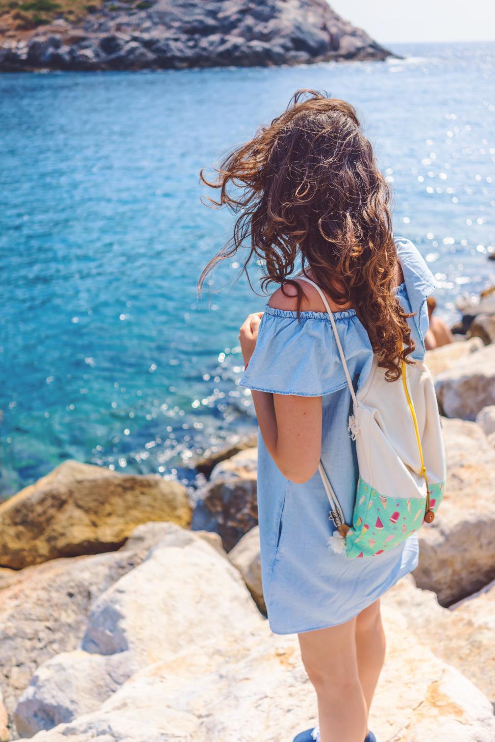 Free Image of Young woman enjoying the view by the sparkling blue ocean 
