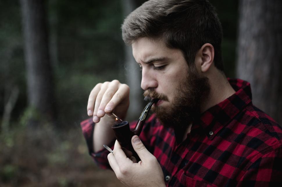 Free Image of Man enjoying a pipe in a forest setting 