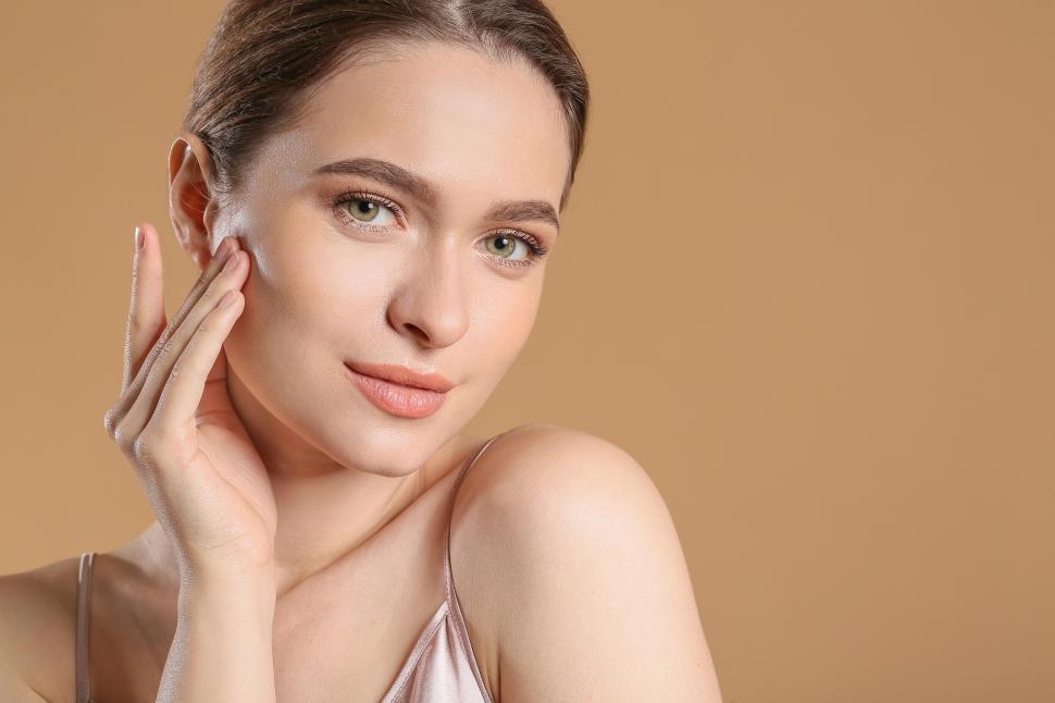 Free Image of Beautiful woman applying skincare in soft lighting 