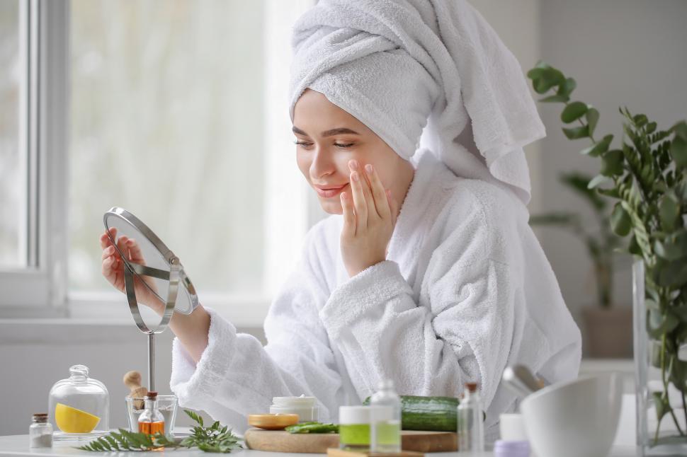 Free Image of Woman applying skincare products while looking in mirror at home 
