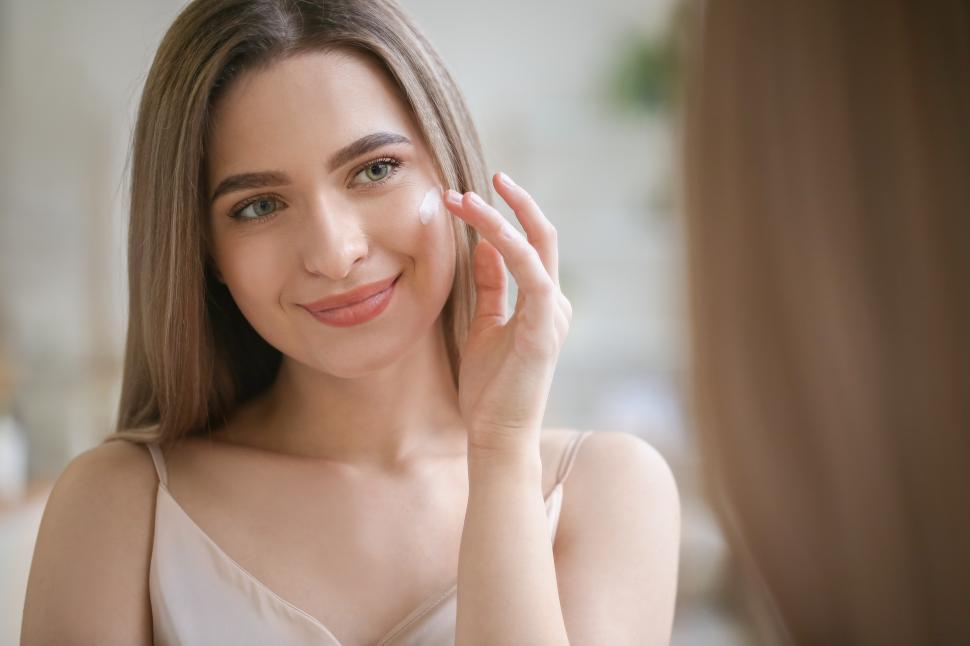 Free Image of Young woman applying skincare product in bright indoor setting 