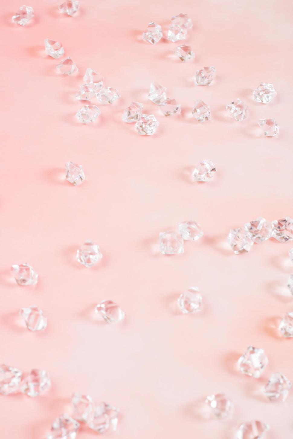 Free Image of Clear crystals scattered on a soft pink surface 