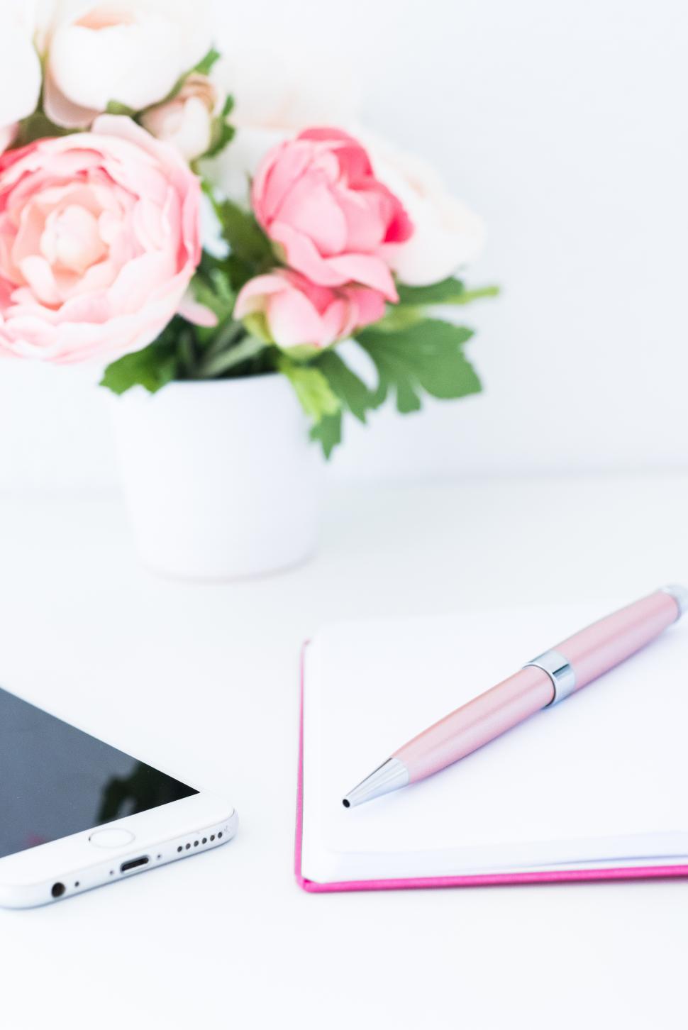 Free Image of Workspace setup with flowers, notebook, and smartphone 