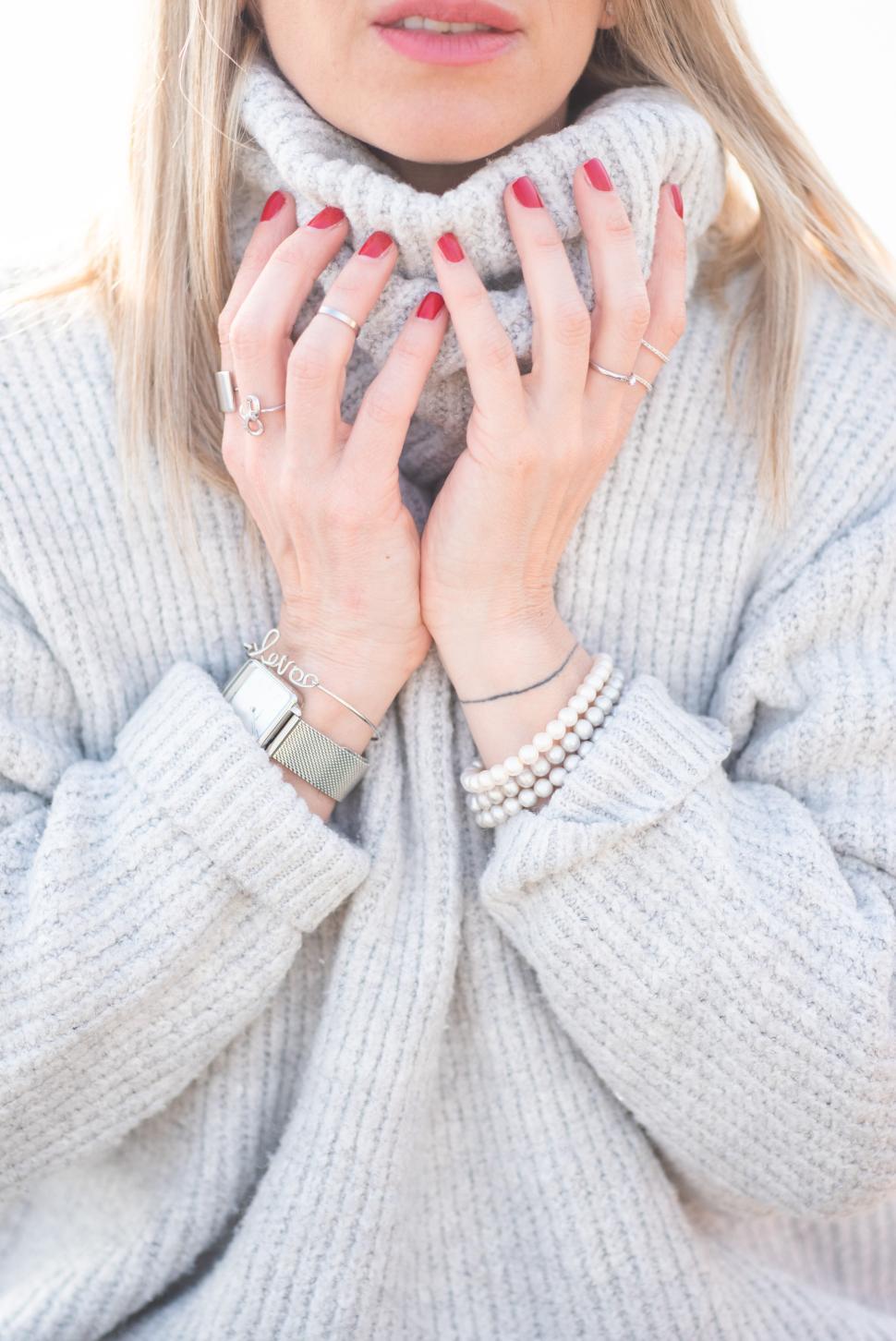 Free Image of Woman wearing a cozy sweater and holding her neck 