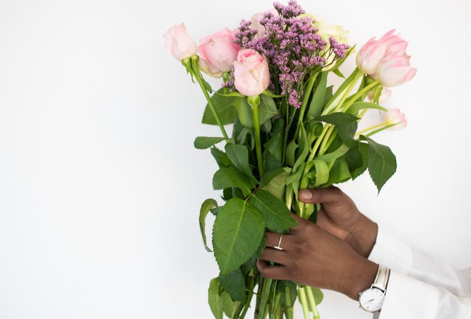 Free Image of Holding a bouquet of pink roses and flowers with greenery 