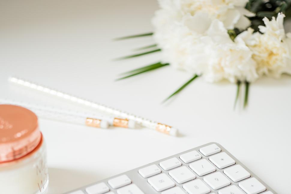 Free Image of Workspace setup with flowers and office supplies on desk 