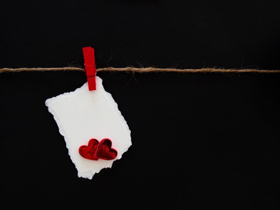 Free Image of Love note hanging on string with red hearts attached against black background 