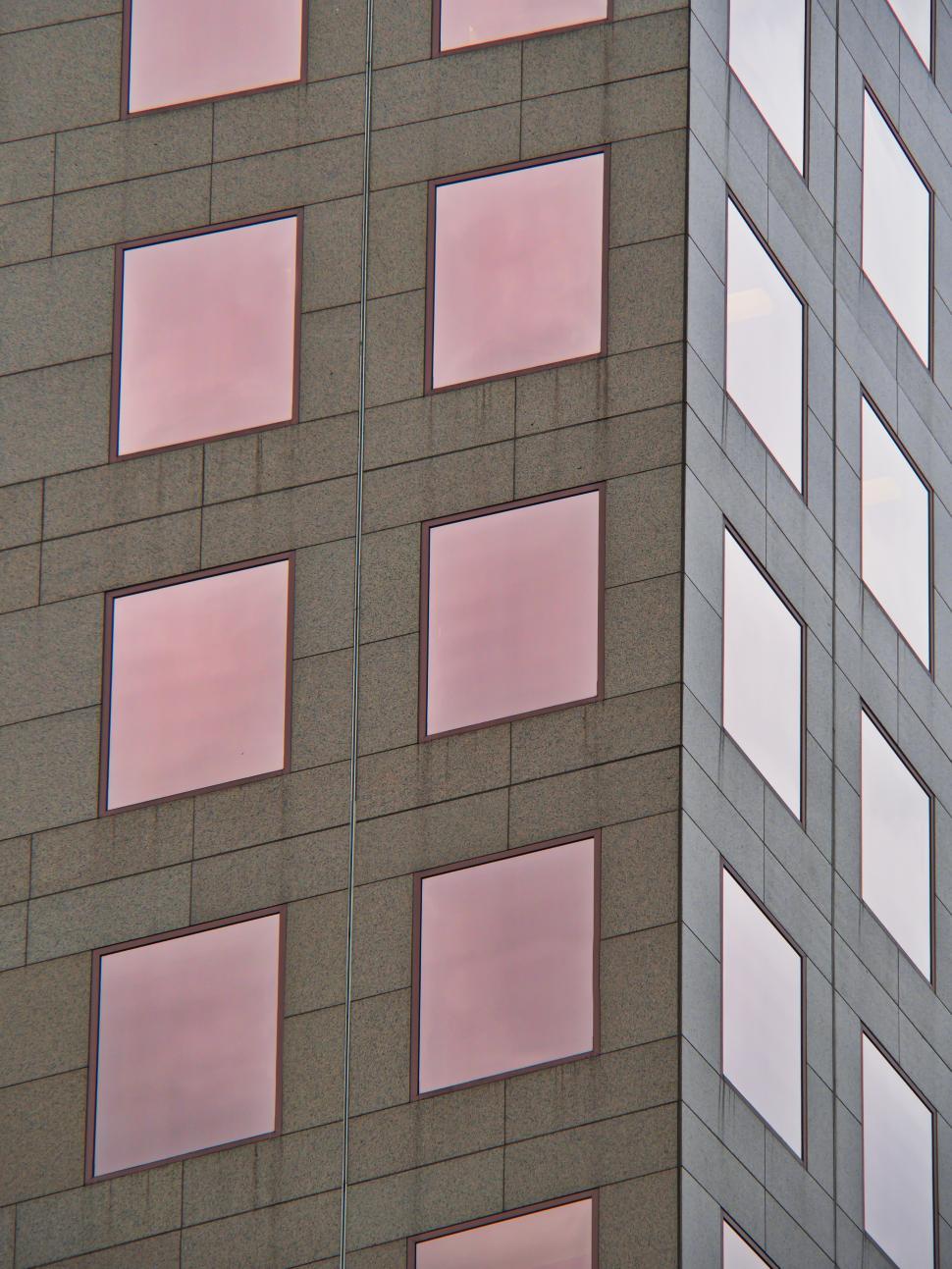 Free Image of Modern building facade with reflective pink glass windows in urban setting 
