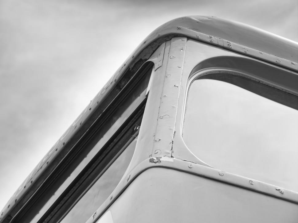 Free Image of Close-up view of an old bus window frame with weathered details under cloudy sky 