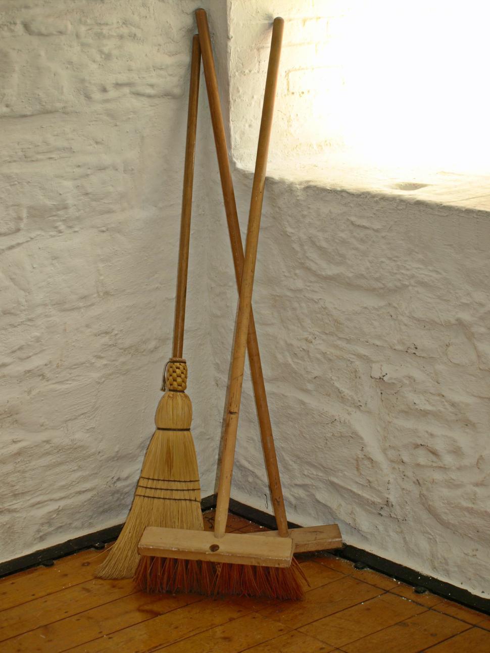 Free Image of Brooms and dustpan resting in a corner of a rustic room 