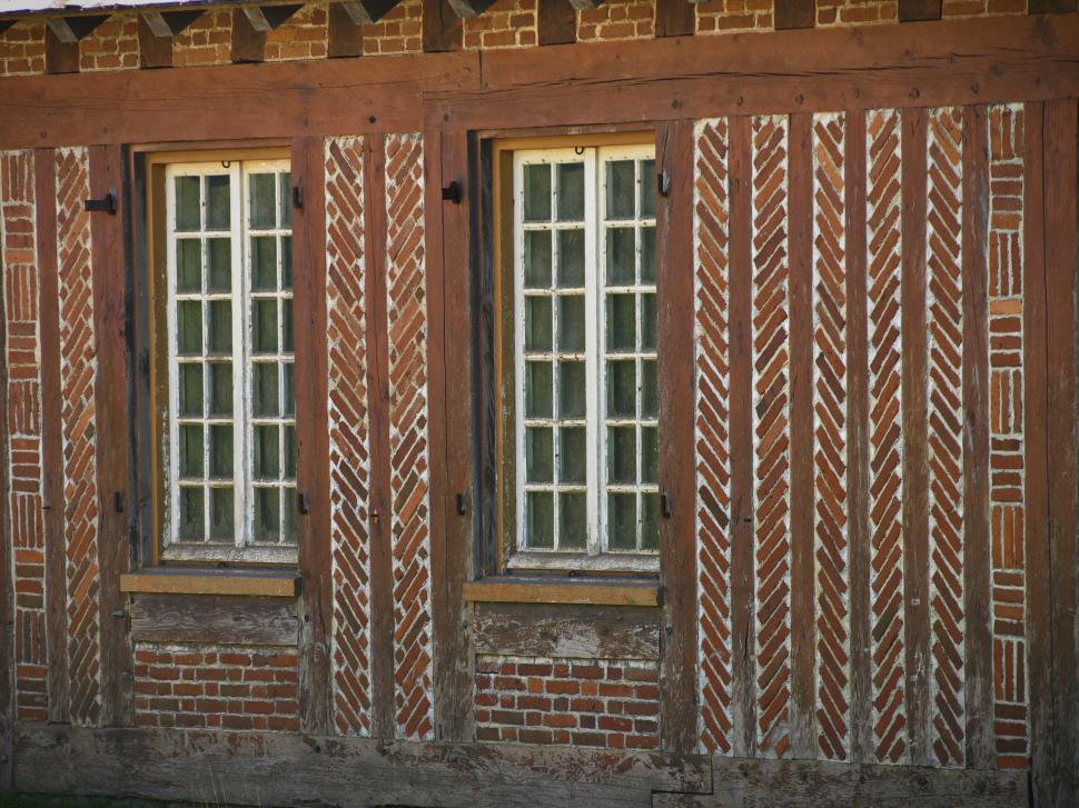 Free Image of Unique brick pattern on rustic building with vintage windows in late afternoon 
