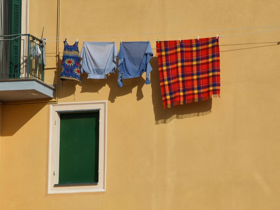 Free Image of Colorful clothing drying on a sunny wall in a charming village 