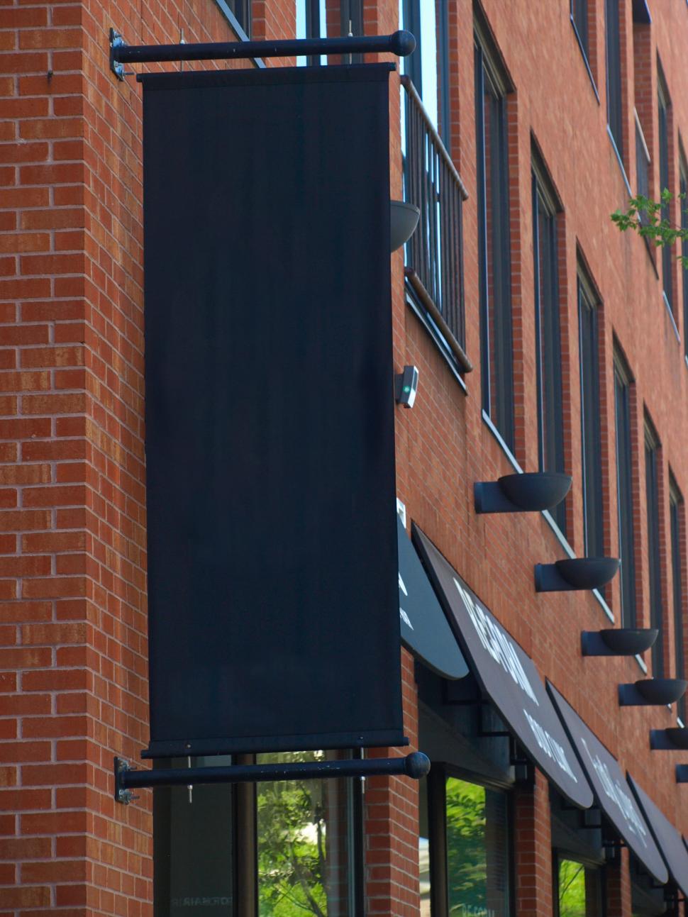 Free Image of Black banner displayed on a red brick building in an urban area 