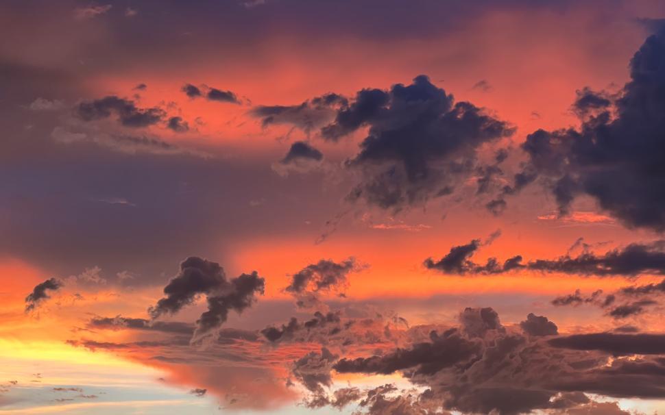 Free Image of Vibrant sunset sky filled with colorful clouds over a serene horizon 
