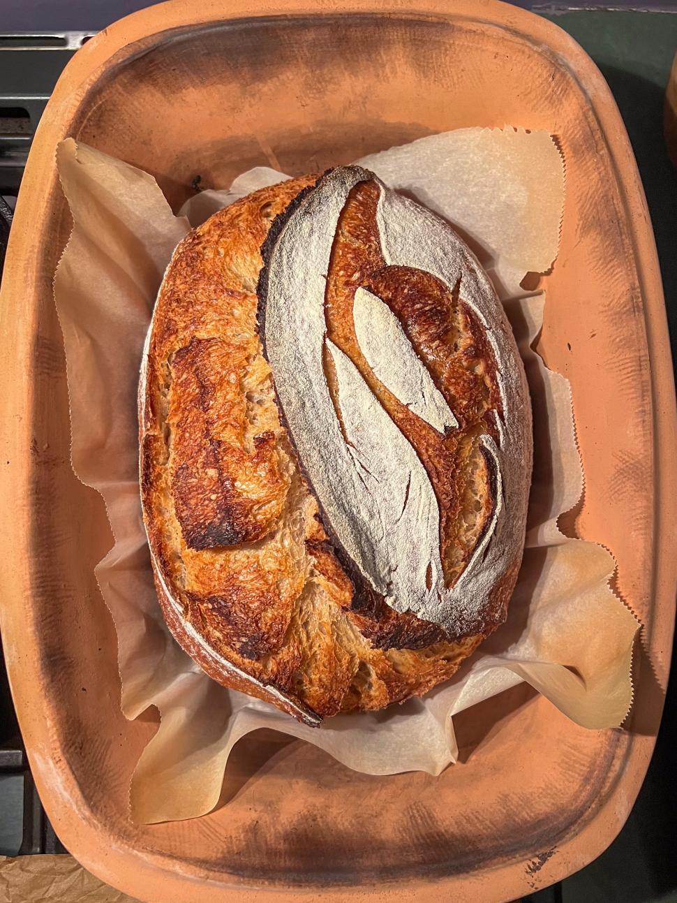 Free Image of Freshly baked artisan sourdough bread in a traditional clay baking dish 