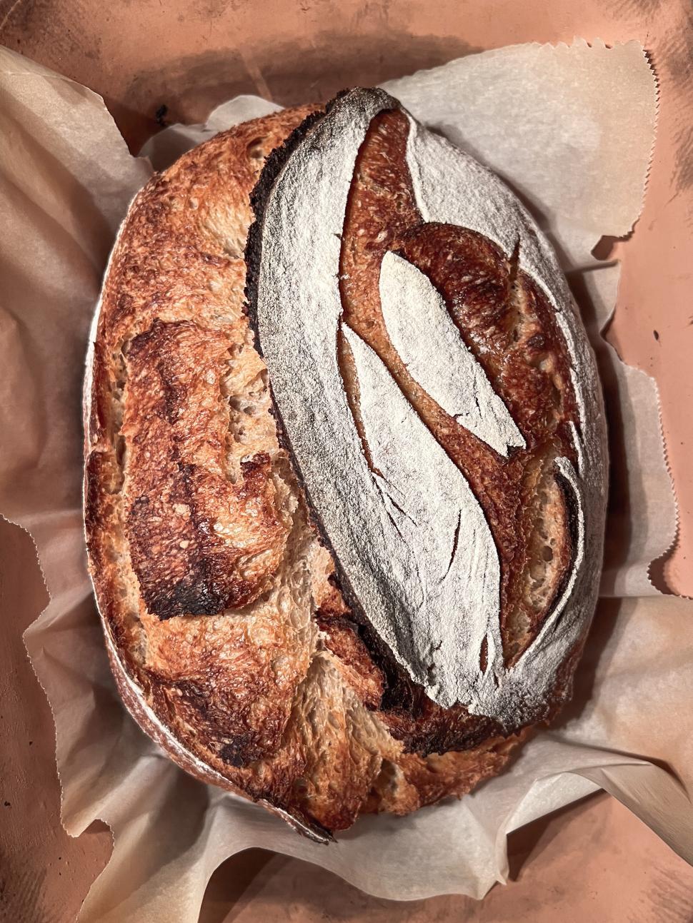 Free Image of Delicious sourdough bread with artistic scoring displayed on parchment paper 