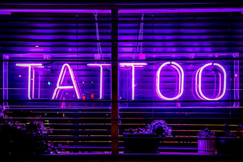Free Image of Vibrant neon tattoo sign illuminates storefront at night 