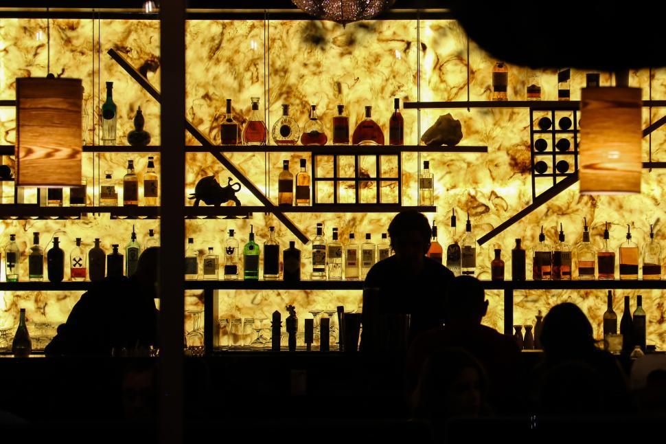 Free Image of Dramatic backlit bar with a variety of liquor bottles in a dimly lit setting 