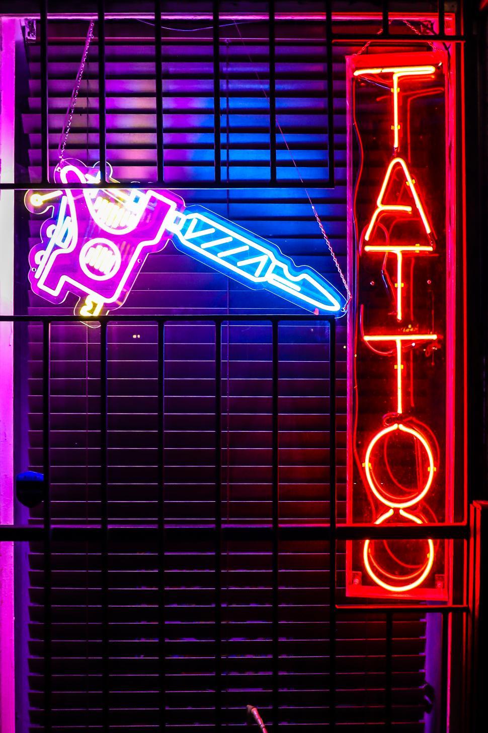 Free Image of Neon tattoo shop sign glowing brightly at night in a vibrant urban area 