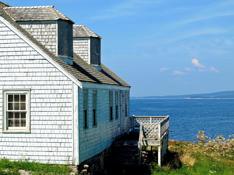 Free Image of Charming coastal house overlooking serene blue waters on a sunny day 