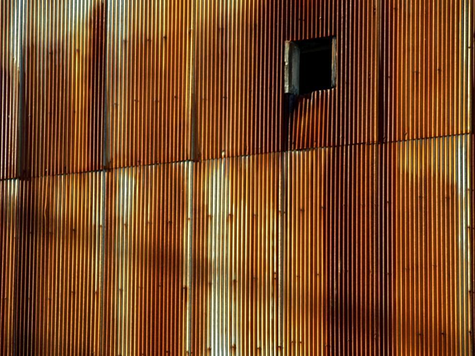 Free Image of Rusty corrugated metal wall with a dark opening in sunlight 