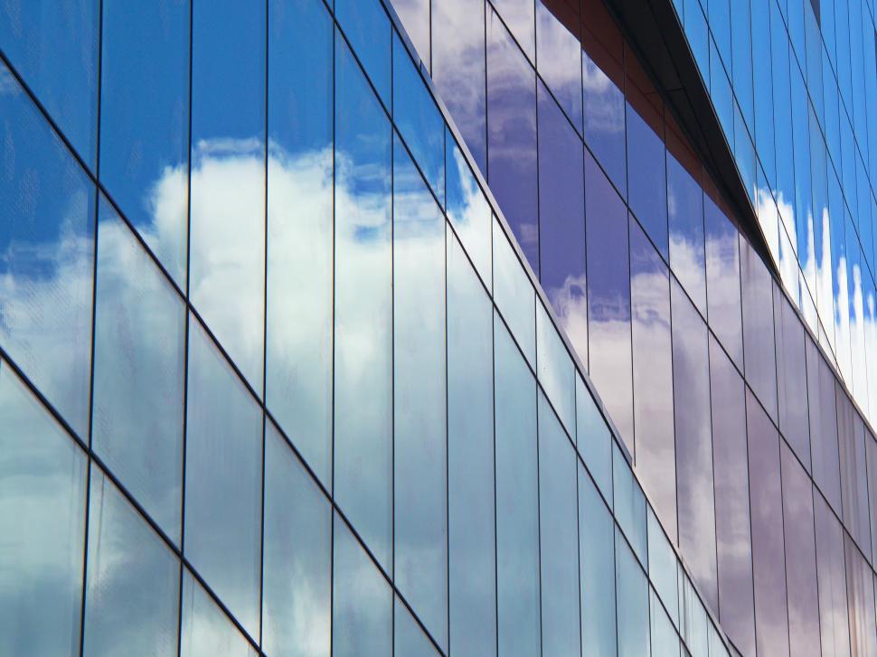 Free Image of Modern building facade reflecting clouds on a sunny day in an urban setting 