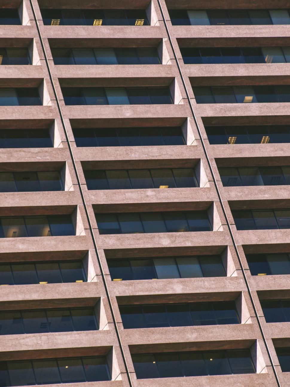 Free Image of Modern office building facade reflecting sunlight with geometric patterns 