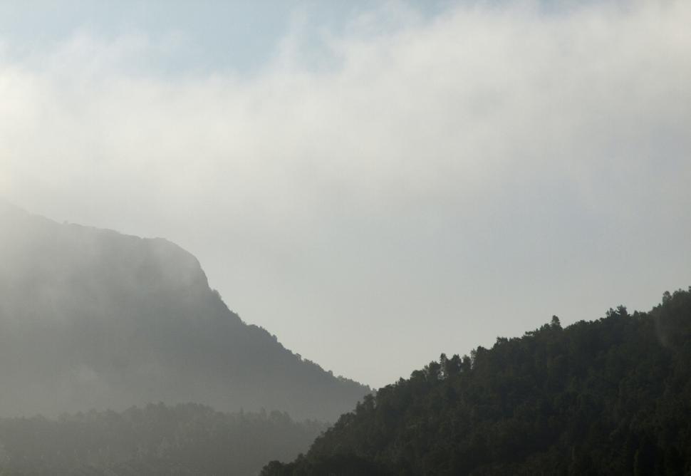 Free Image of Misty mountain landscape featuring peaks and forested hills in the morning light 