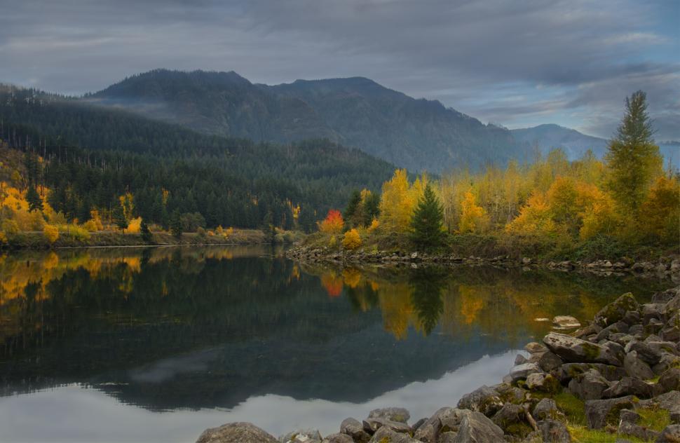 Free Image of Autumn colors reflect on tranquil lake surrounded by mountains 