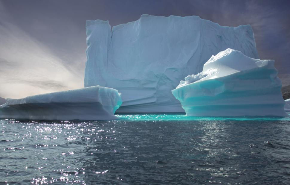 Free Image of Icebergs floating in calm Arctic waters under a cloudy sky 