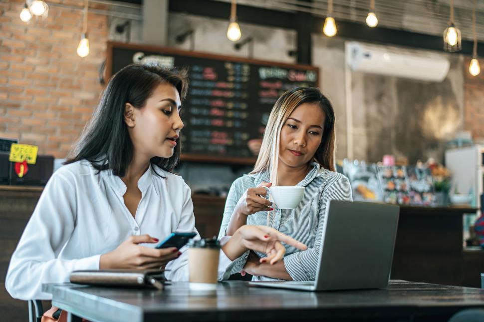 Free Image of Two women sitting and working with a laptop in a coffee shop 