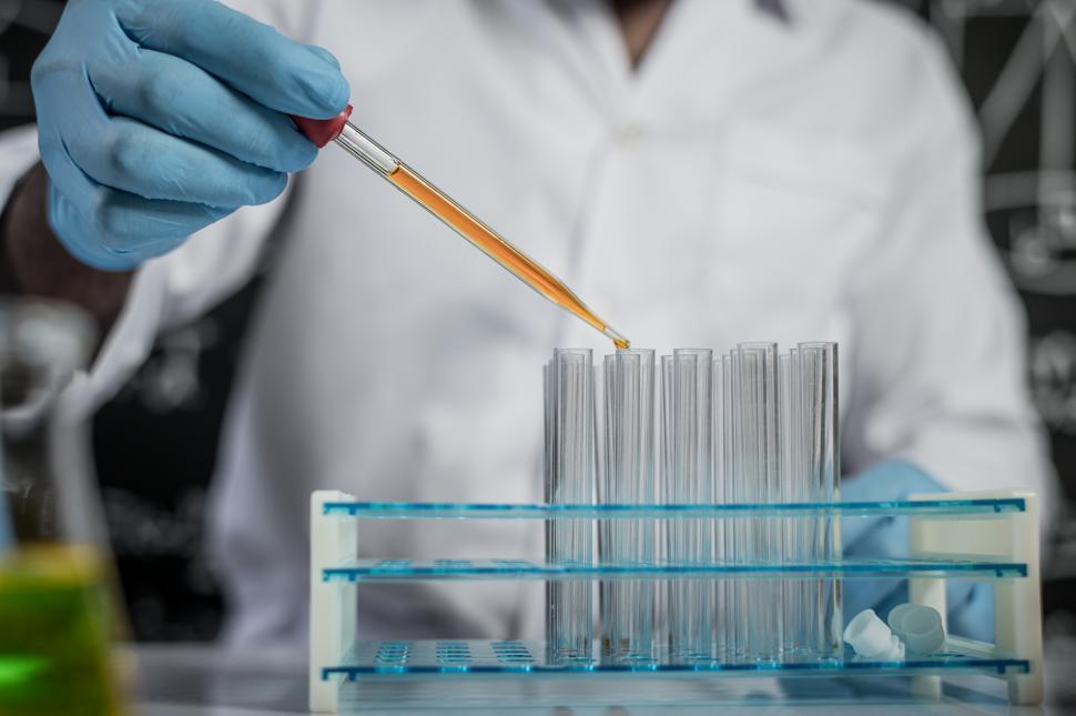 Free Image of Scientists drop orange chemicals into the glass at the laboratory. 